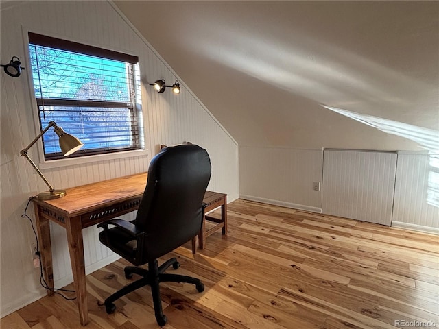 office featuring lofted ceiling, light hardwood / wood-style floors, and wood walls