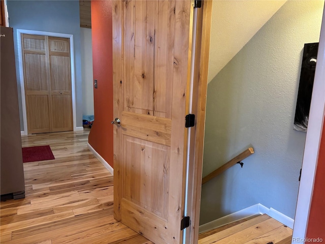 hallway with light hardwood / wood-style flooring and vaulted ceiling