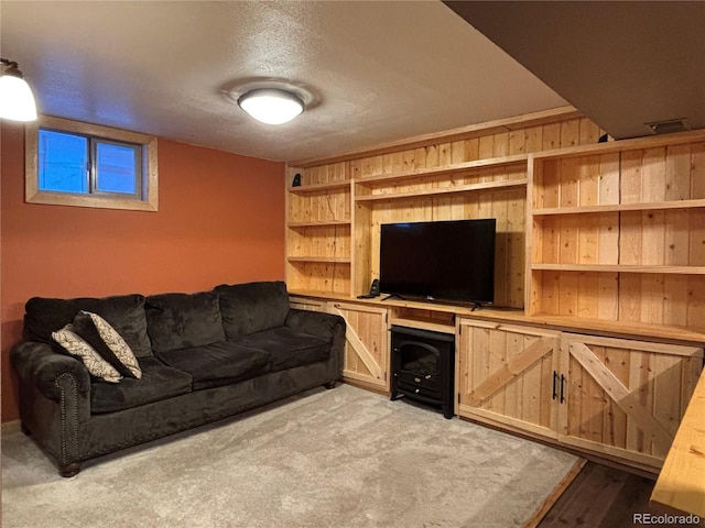 carpeted living room with built in features, a textured ceiling, and wood walls