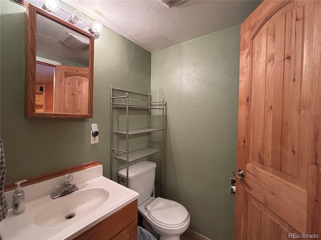 bathroom with vanity, toilet, and a textured ceiling