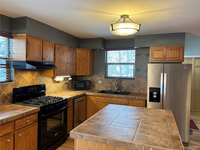 kitchen with sink, tile countertops, a wealth of natural light, decorative backsplash, and black appliances