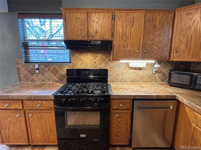 kitchen featuring backsplash, tile countertops, and black appliances