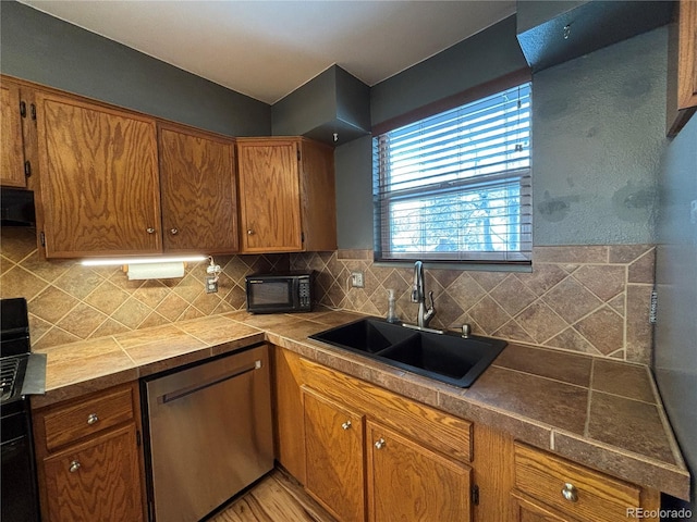 kitchen featuring tasteful backsplash, stainless steel dishwasher, light hardwood / wood-style floors, and sink