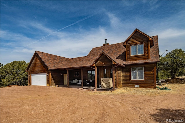 view of front of property with an attached garage, a patio, and dirt driveway