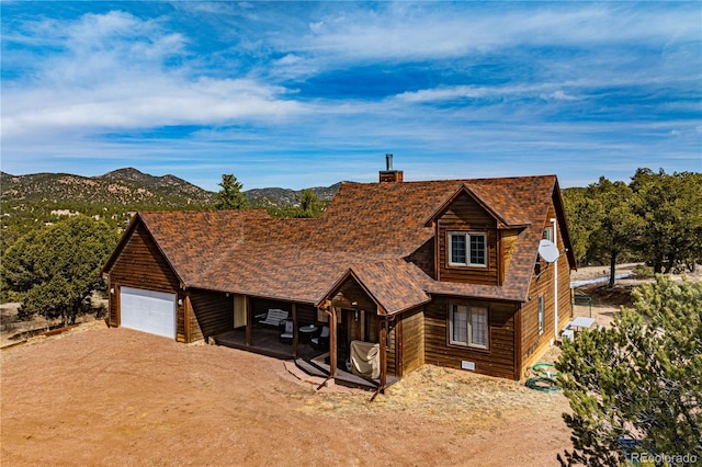 chalet / cabin featuring a mountain view, a chimney, and driveway