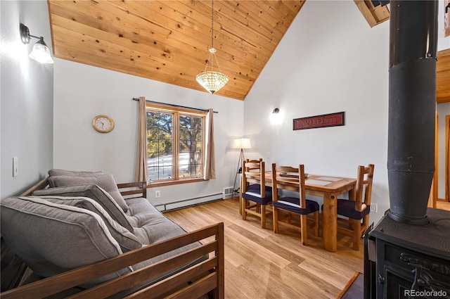 living area with high vaulted ceiling, a baseboard heating unit, light wood-style floors, wooden ceiling, and a wood stove