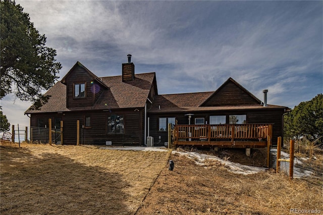 back of property with a wooden deck, a chimney, and a shingled roof