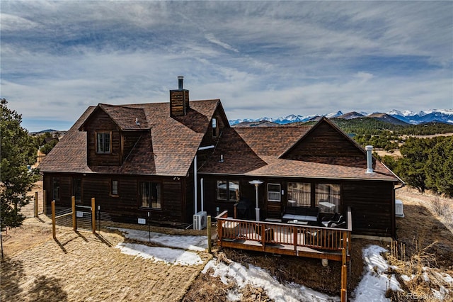 back of property featuring a mountain view, roof with shingles, cooling unit, and a chimney