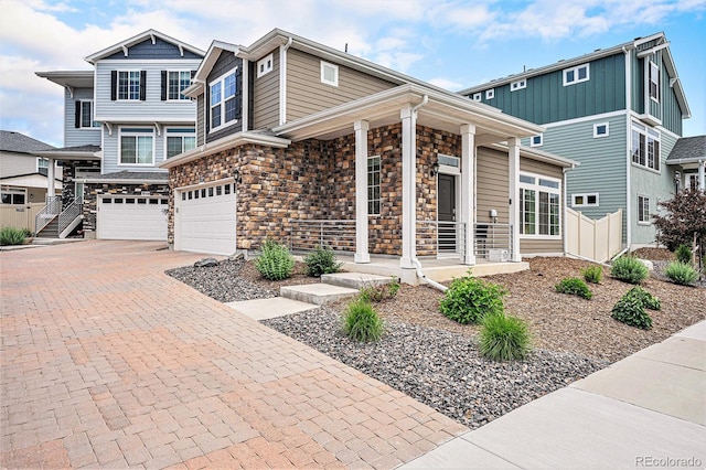 3934 N Quatar Ct, Aurora, CO 80019 - view of front facade with a porch, a garage, stone siding, and decorative driveway