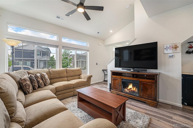 3934 N Quatar Ct, Aurora, CO 80019 - living room featuring ceiling fan, light wood-type flooring, a glass covered fireplace, high vaulted ceiling, and recessed lighting