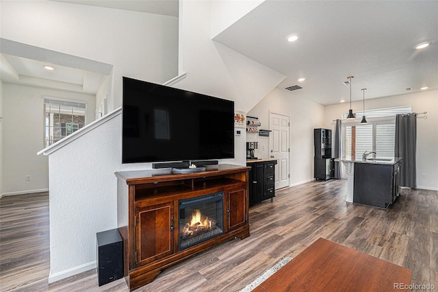 3934 N Quatar Ct, Aurora, CO 80019 - living area featuring dark wood-style floors, a glass covered fireplace, and recessed lighting