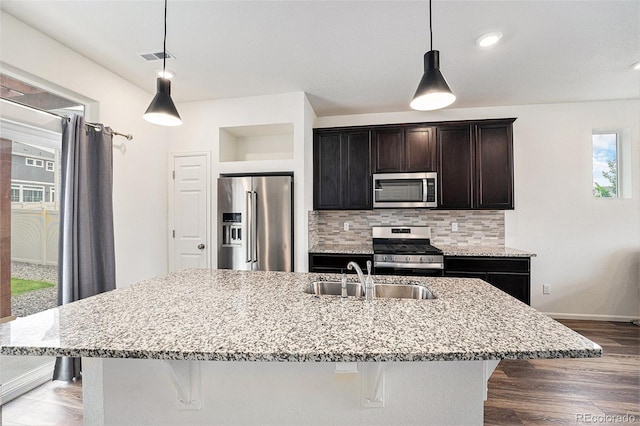 3934 N Quatar Ct, Aurora, CO 80019 - kitchen with appliances with stainless steel finishes, backsplash, light stone counters, a kitchen bar, and recessed lighting