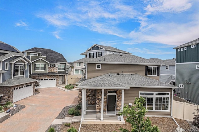 3934 N Quatar Ct, Aurora, CO 80019 - rear view of property with stone siding, decorative driveway, a garage, a shingled roof, and a residential view