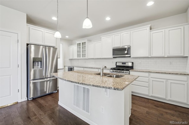 kitchen featuring white cabinets, light stone counters, pendant lighting, a kitchen island with sink, and appliances with stainless steel finishes