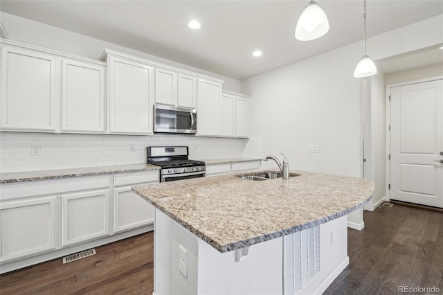 kitchen with stainless steel appliances, an island with sink, tasteful backsplash, white cabinetry, and sink