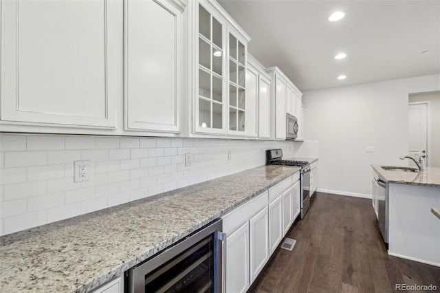 kitchen featuring white cabinets, beverage cooler, appliances with stainless steel finishes, and sink