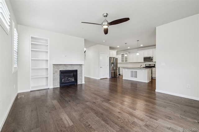 unfurnished living room featuring ceiling fan, dark hardwood / wood-style floors, and built in shelves