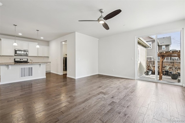 unfurnished living room with ceiling fan and dark hardwood / wood-style flooring