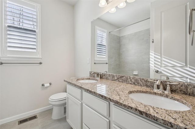 bathroom featuring tile patterned floors, a tile shower, vanity, and toilet