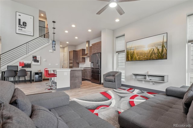 living room featuring ceiling fan, sink, and light hardwood / wood-style floors