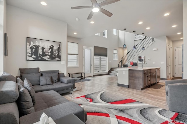 living room featuring ceiling fan, sink, and light wood-type flooring