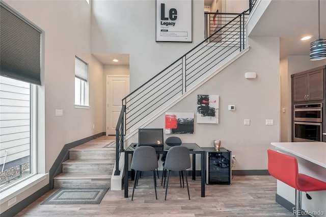 dining area featuring a high ceiling, hardwood / wood-style floors, and wine cooler