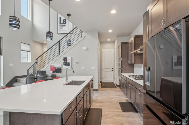 kitchen featuring appliances with stainless steel finishes, a kitchen island with sink, sink, and dark brown cabinets