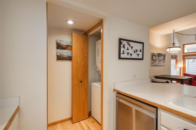 23624 Pondview Pl Unit G, Golden, CO 80401 - kitchen with stacked washer and clothes dryer, stainless steel dishwasher, light wood finished floors, light countertops, and white cabinets