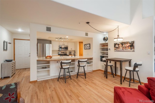 23624 Pondview Pl Unit G, Golden, CO 80401 - kitchen with light wood-style flooring, a kitchen breakfast bar, open shelves, stainless steel appliances, and a peninsula