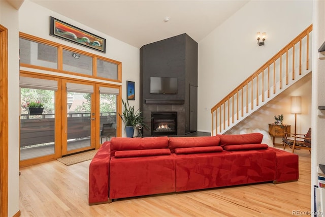 23624 Pondview Pl Unit G, Golden, CO 80401 - living room featuring high vaulted ceiling, wood finished floors, a large fireplace, stairs, and french doors