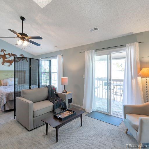 living area with carpet, a ceiling fan, a textured ceiling, and vaulted ceiling