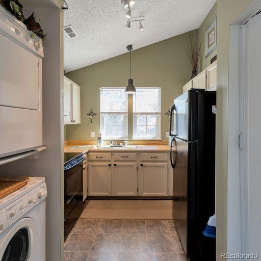 kitchen featuring freestanding refrigerator, stove, a textured ceiling, vaulted ceiling, and light countertops