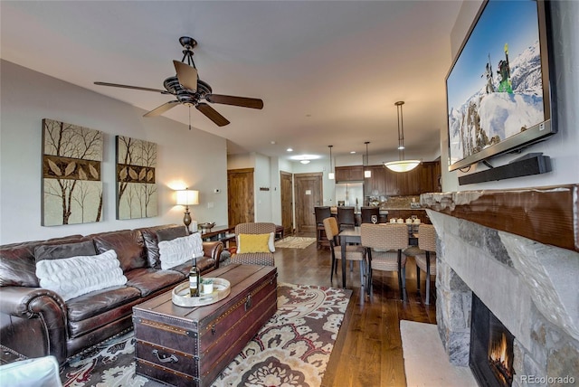 living room with dark hardwood / wood-style floors, ceiling fan, and a fireplace