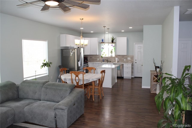 living area featuring dark wood-type flooring, ceiling fan, a chandelier, and recessed lighting