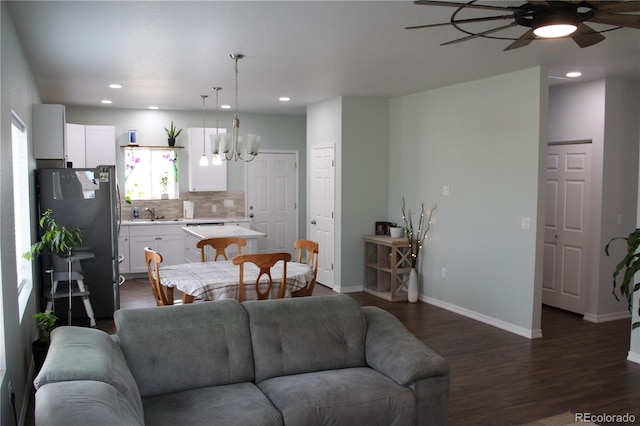 living room featuring ceiling fan, dark wood-type flooring, baseboards, recessed lighting, and a chandelier