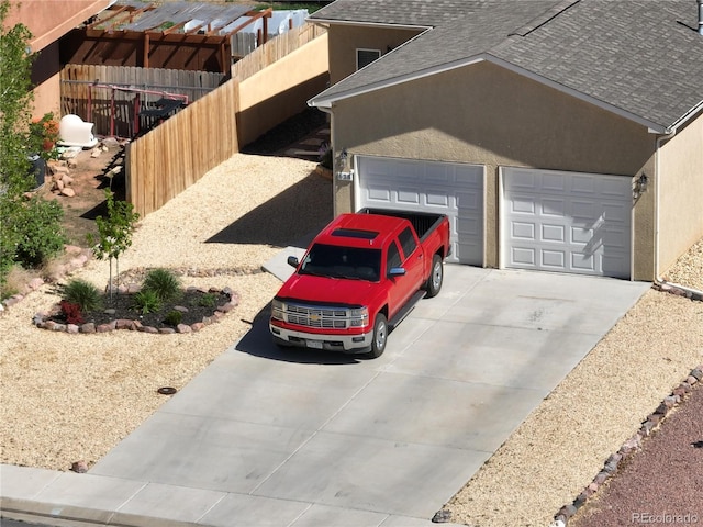 view of home's exterior with a shingled roof, stucco siding, concrete driveway, a garage, and fence