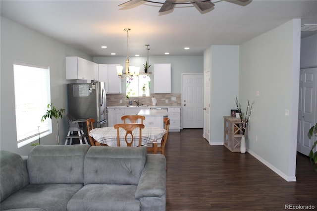 living area featuring a ceiling fan, dark wood-type flooring, baseboards, recessed lighting, and a chandelier