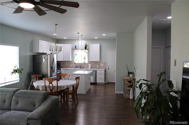 kitchen featuring stainless steel appliances, light countertops, open floor plan, decorative backsplash, and dark wood-style floors