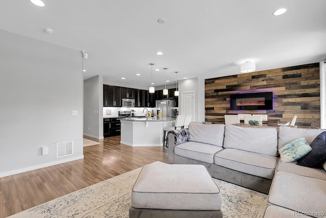 19210 E Pacific Pl, Aurora, CO 80013 - living room featuring wood walls, light wood-style flooring, and recessed lighting