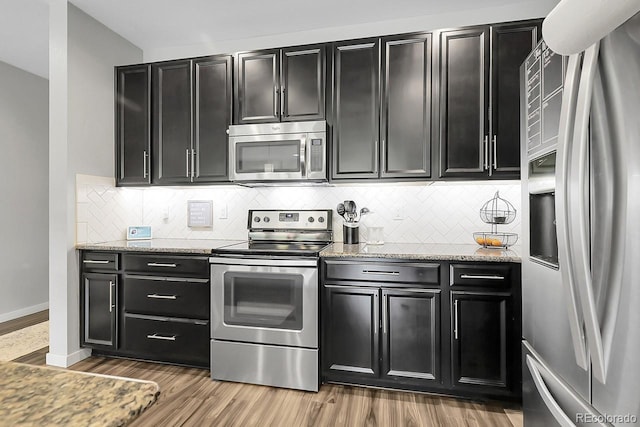 19210 E Pacific Pl, Aurora, CO 80013 - kitchen with appliances with stainless steel finishes, dark cabinetry, wood finished floors, and tasteful backsplash