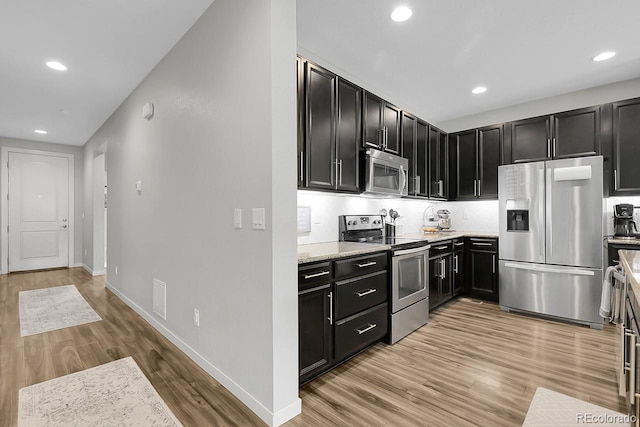 19210 E Pacific Pl, Aurora, CO 80013 - kitchen with stainless steel appliances, light wood-style flooring, recessed lighting, dark cabinets, and light stone counters