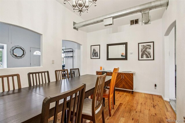 915 26th St, Denver, CO 80205 - dining room featuring arched walkways, light wood finished floors, a chandelier, and a towering ceiling