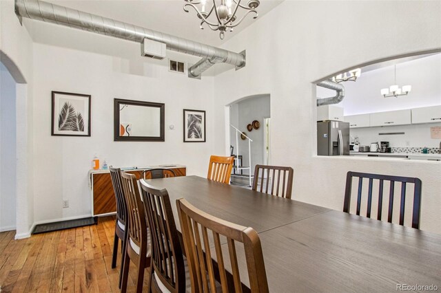 915 26th St, Denver, CO 80205 - dining area featuring a chandelier, arched walkways, and light wood finished floors