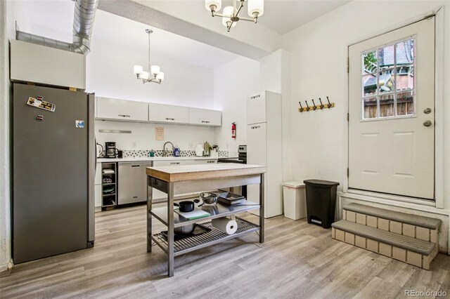 915 26th St, Denver, CO 80205 - kitchen with stainless steel appliances, a chandelier, light countertops, and light wood-type flooring