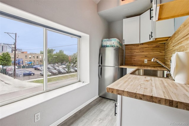 915 26th St, Denver, CO 80205 - kitchen with freestanding refrigerator, light wood-style floors, wood counters, and white cabinets
