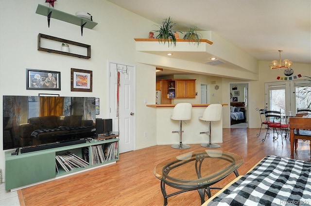 living area featuring french doors, visible vents, vaulted ceiling, a notable chandelier, and light wood-style floors
