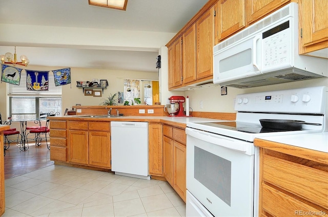 kitchen featuring light countertops, light tile patterned floors, a sink, a peninsula, and white appliances