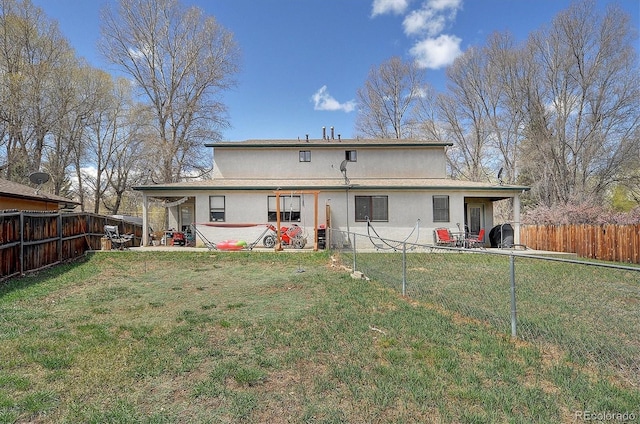 back of house with a lawn, a fenced backyard, a patio area, and stucco siding