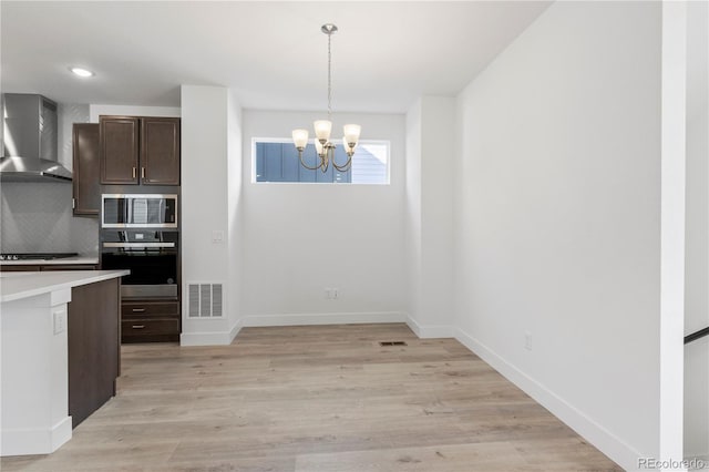 5271 Rendezvous Pkwy, Timnath, CO 80547 - kitchen with appliances with stainless steel finishes, wall chimney exhaust hood, a chandelier, light countertops, and decorative backsplash