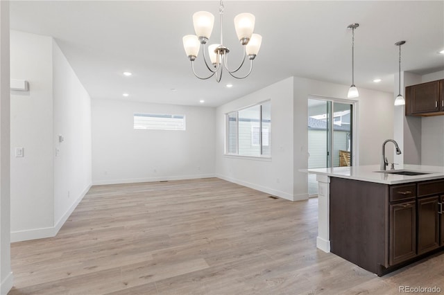 5271 Rendezvous Pkwy, Timnath, CO 80547 - kitchen featuring a sink, light countertops, dark brown cabinets, decorative light fixtures, and light wood-type flooring